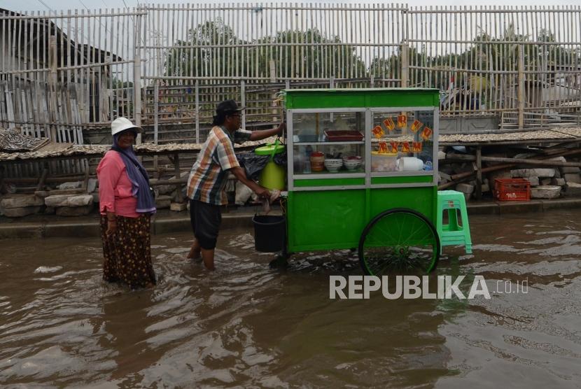 Warga melintasai kawasan yang terkena  banjir rob  di Kampung Nelayan Muara Angke di Penjaringan, Jakarta, Senin (26/11).