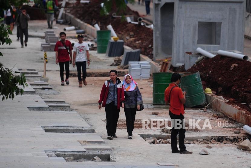 Warga berjalan kaki di dekat proyek penataan trotoar di kawasan Sudirman, Jakarta Pusat.
