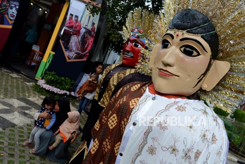 Pengunjung saat berfoto dengan ondel-ondel pada acara Festival Warisan Budaya Tak Benda di kawasan Setu Babakan, Jakarta, Ahad (28/4).