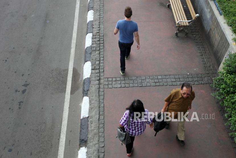 Sejumlah pekerja kantor berjalan di Trotoar Kawasan MH Thamrin, Jakarta, Rabu (7/3).