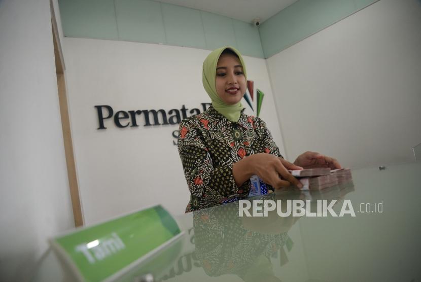Petugas melayani transaksi nasabah di kantor layanan Permata Bank.