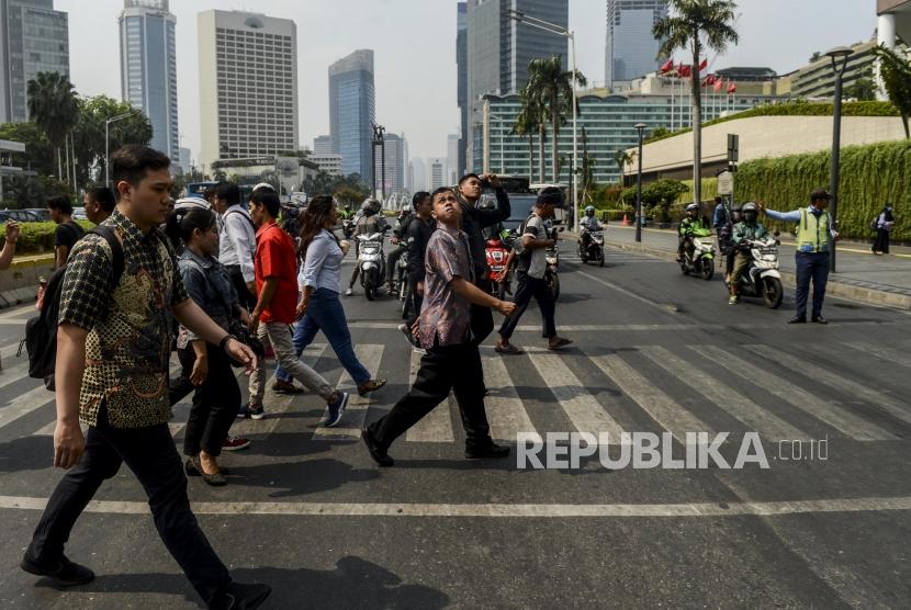 Sejumlah karyawan menggunakan baju batik saat melintasi pelican crossing di kawasan Bundaran HI, Jakarta, Rabu (2/10).