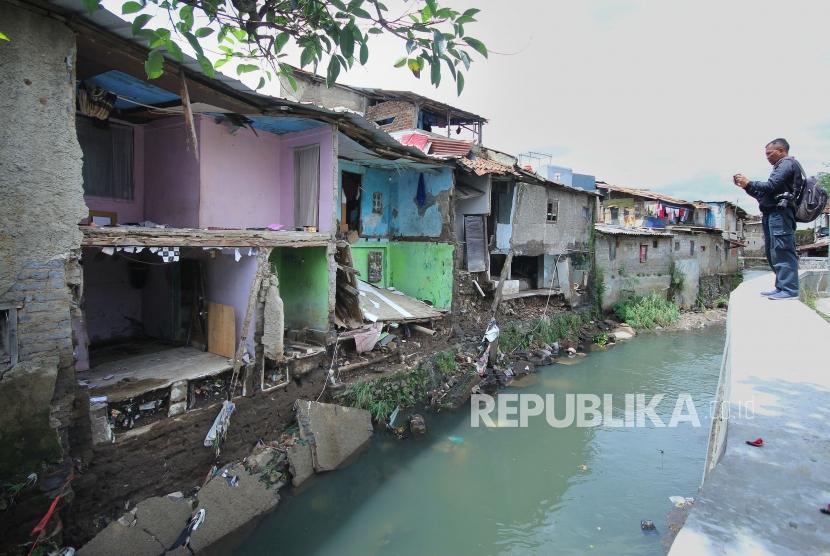Seorang wartawan memotret kondisi rumah yang ambruk di pinggiran Sungai Citepus, Kawasan Sirnaraga, Kota Bandung.
