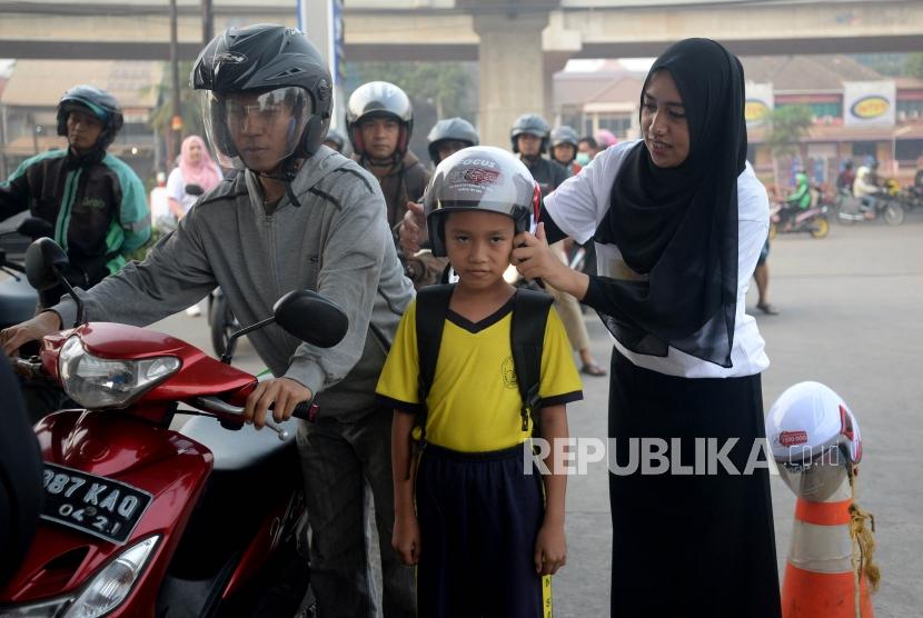 (ILUSTRASI) Petugas memasangkan helm kepada anak yang diajak berkendara.