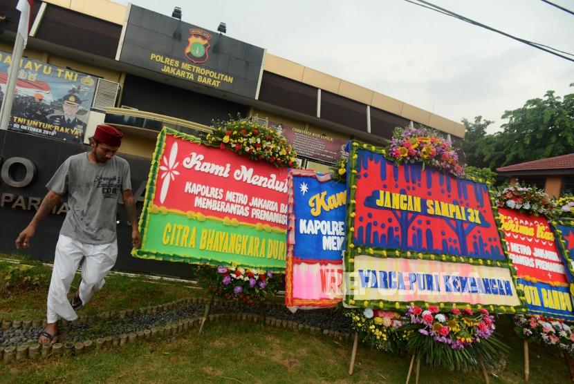 Pekerja saat memasang karangan bunga di depan Mapolres Metro Jakarta Barat, Kamis (22/11).