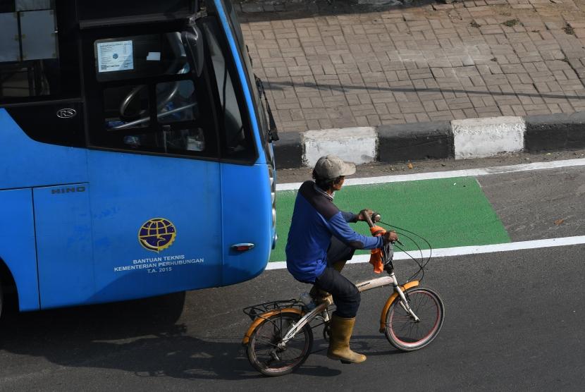 Pengendara sepeda tidak bisa melintasi jalur sepeda karena bus memanfaatkannya untuk tempat parkir.
