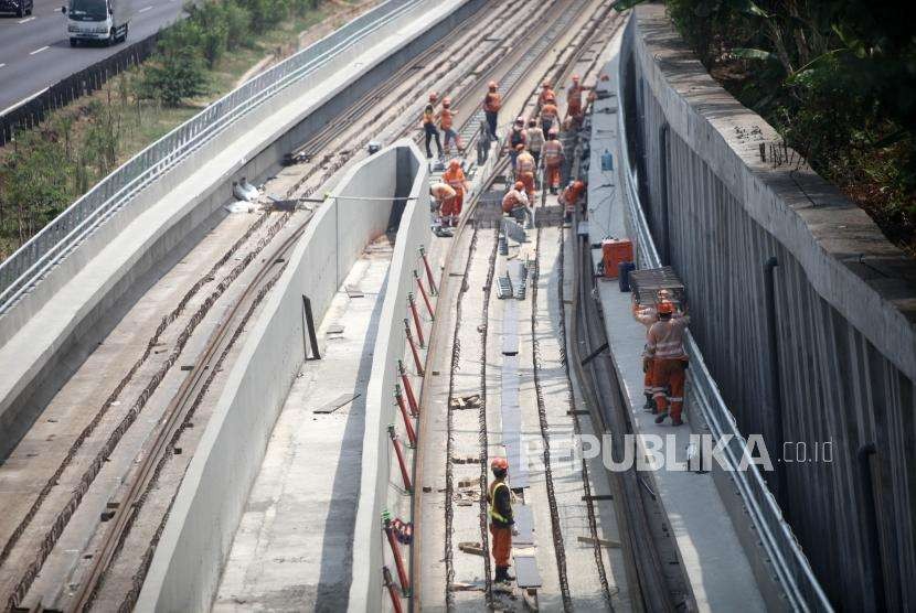 Pekerja menyelesaikan pemasangan rel Kereta Light Rail Transit (LRT) Jabodebek di kawasan Kampung Makassar, Jakarta. Proyek LRT Jakarta termasuk salah satu proyek infrastruktur yang mendapat garansi dari Badan Usaha Penjaminan Infrastruktur (BUPI).