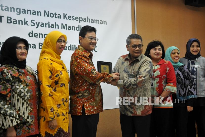 Direktur Wholesale Banking Mandiri Syariah Kusman Yandi (empat kanan) bersama Direktur Utama PT Pertamina Bina Medika (PT PBM) DR Dany Amrul Ichdan (ketiga kiri) bersama jajaran usai melakukan penandatanganan nota kesepahaman di Jakarta, Selasa (28/11).