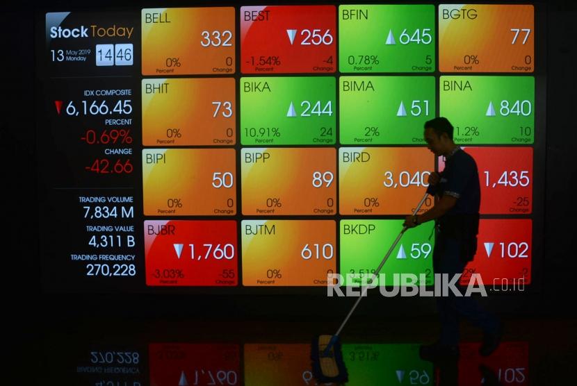 Karyawan melintas di depan layar pergerakan saham di Bursa Efek Indonesia, Jakarta, Senin (13/5).