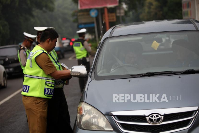 Petugas gabungan melakukan penertiban pajak kendaraan bermotor saat razia pengesahan Surat Tanda Nomor Kendaraan (STNK) di Jalan Raya Kalibata, Jakarta Selatan, Selasa (24/4).