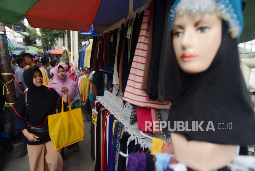 Warga saat akan membeli kerudung yang dijual oleh PKL di Jalan Jatibaru, Tanah Abang, Jakarta, Senin (3/12).