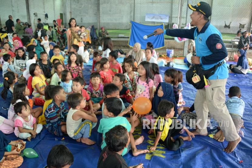 Anak-anak pengungsi korban bencana Tsunami mendengarkan hiburan dan permainan dari petugas Kementerian Sosial di Posko Pengungsi Labuan ,Banten, Senin (24/12).