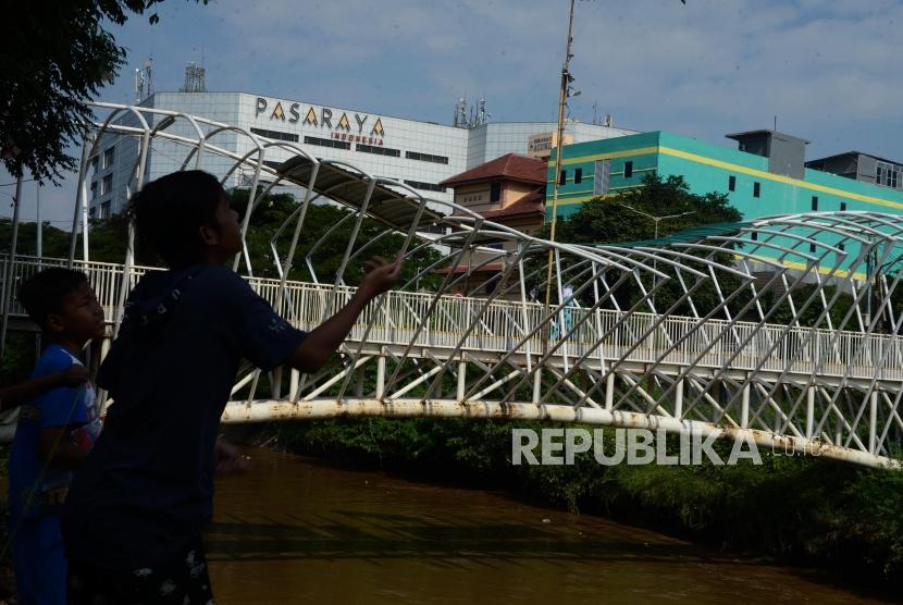 Anak-anak bermain dengan latar belakang jembatan penyeberangan orang (JPO) Jayakarta di kawasan Menteng, Jakarta.