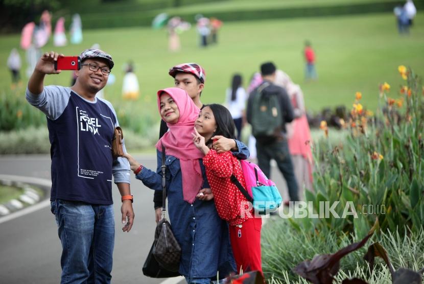 Warga berfoto selfie saat berwisata di Kebun Raya Bogor, Jawa Barat, Sabtu (23/12).