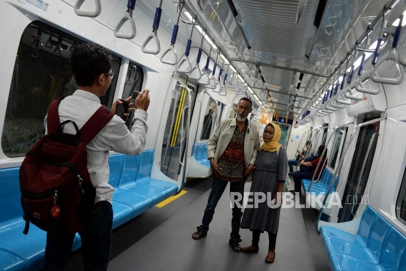 Warga berfoto saat menaiki kereta MRT di Stasiun Bundaran HI, Jakarta, Senin (25/3).