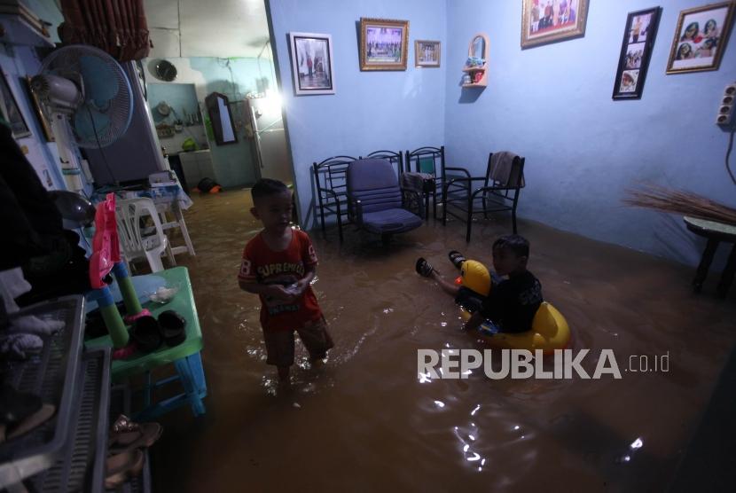 Children play at a house flooded due to the overflowing of the Ciliwung river at Kebon Pala, Kampung Melayu, Jakarta has , Senin (5/2).