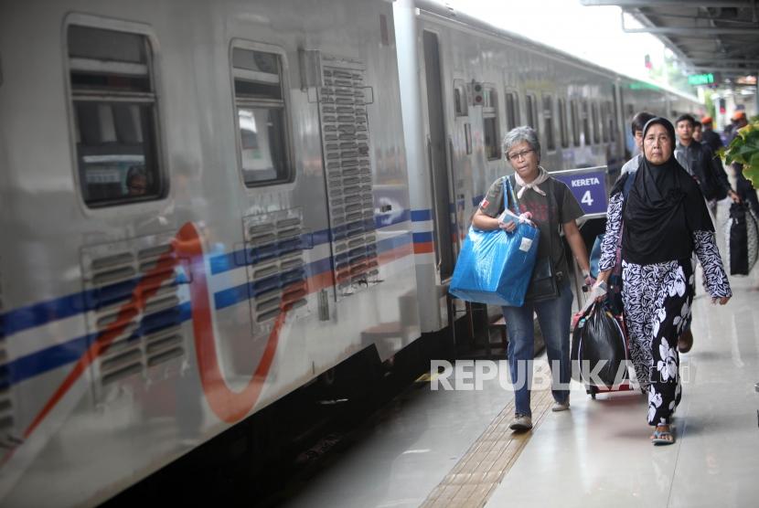 Penumpang berjalan saat akan menaiki kereta api di Stasiun Pasar Senen, Jakarta, Selasa (26/12).