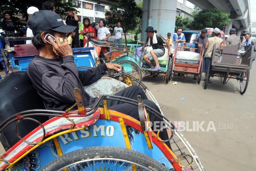 Tukang becak saat menunggu untuk didata oleh petugas di kolong flyover Bandengan Utara, Pekojan, Tambora, Jakarta Barat, Jumat (26/1).