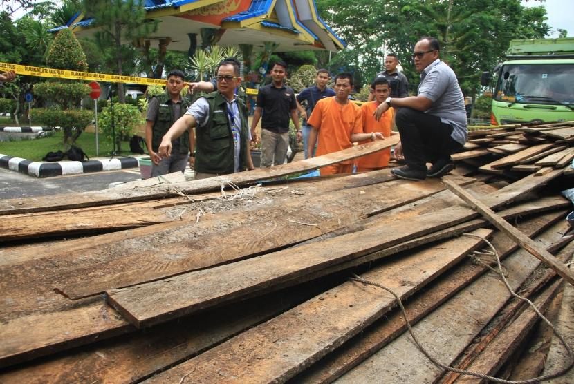 Direktur Reserse Kriminal Khusus Polda Riau, Kombes Pol Arif Gideon Setiawan (kanan) memeriksa barang bukti kayu hasil pembalakan liar, di Kota Pekanbaru, Kamis (11/10).