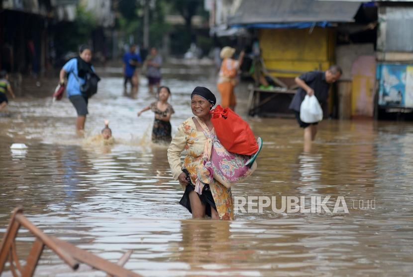 Warga melintasi genangan saat banjir melanda ruas jalan Jatinegara Barat, Jakarta, Selasa(6/2).