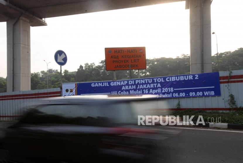 Kendaraan melintas disamping spanduk himbauan saat pemberlakuan ganjil genap di Gerbang Tol Cibubur2, Jakarta Timur, Senin (16/4).