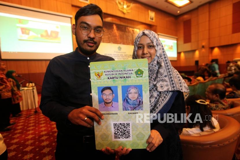 Pasangan suami istri menunjukan kartu nikahnya seusai peresmian Aplikasi Pencatatan Nikah (SIMKAH) Web dan Kartu Nikah di Auditorium Kementerian Agama, Jakarta, Kamis (8/11).