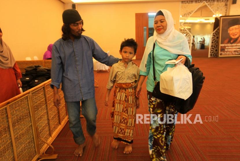 Seorang anak didamping orang tuanya berjalan seusai mengikuti Khitanan Massal dalam rangka Bulan HM Soeharto di Komplek Masjid At-Tin, Jakarta Timur, Ahad (11/3).
