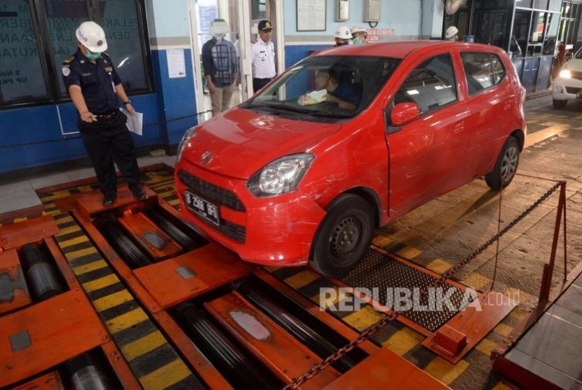 Petugas memeriksa mobil taksi daring saat uji kir di Unit Pengelola Pengujian Kendaraan Bermotor (UP-PKB) Pulogadung, Jakarta, Ahad (5/11).