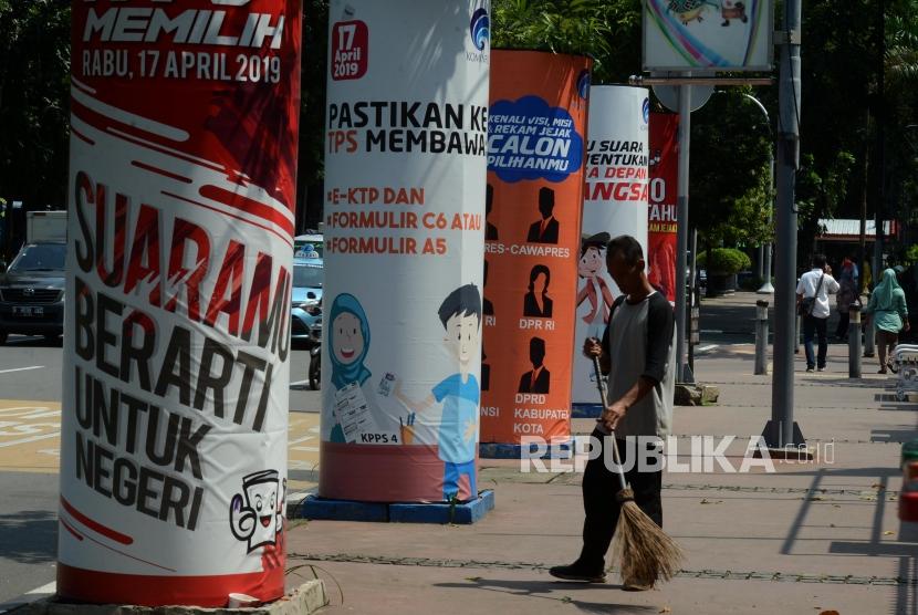 Target Partisipan Pemilu 2019. Petugas menyapu di dekat spanduk sosialisasi Pemilu 2019 di Jalan Medan Merdeka Barat, Gambir, Jakarta, Senin (25/2).