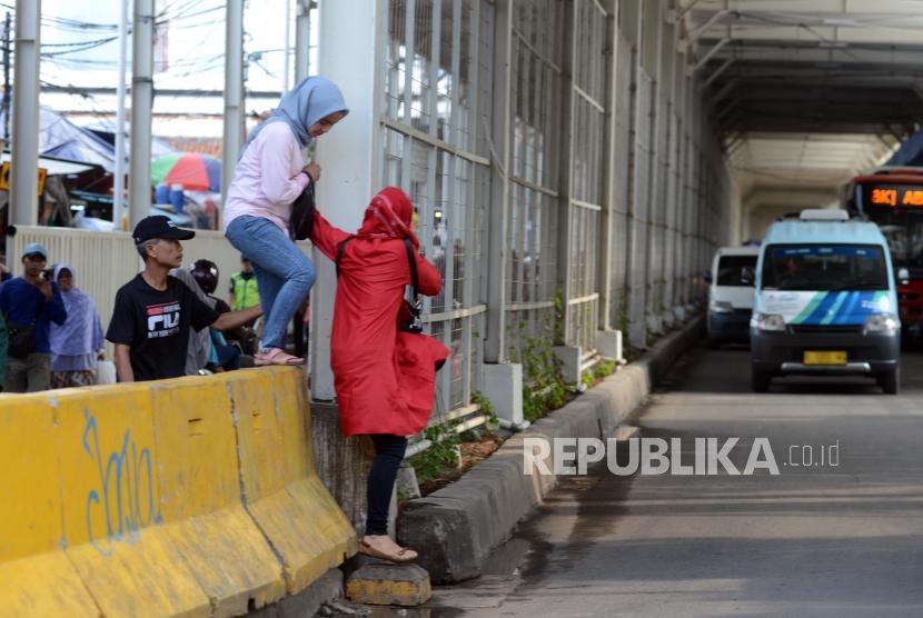 Warga melintasi pagar beton pembatas jalan di Jalan Jatibaru, Tanah Abang, Jakarta, Rabu (9/1).
