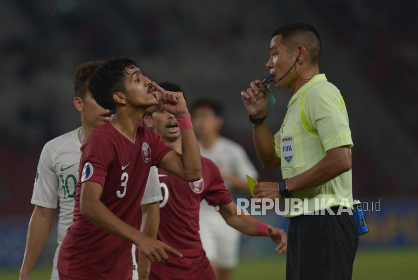 Pemain Bertahan Qatar  Ahmed Albakheet  memprotes wasit  Sivakorn Pu-Udom saat melawan Indonesia dalam pertandingan grup a Piala AFC U-19 di Stadion Utama Gelora Bung Karno, Jakarta, Ahad (21/10).