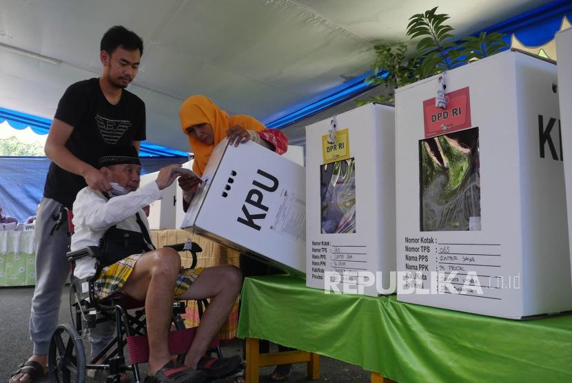 Seorang pemilih lansia dibantu petugas KPPS memasukkan surat suaranya kedalam kotak suara di TPS 65, kelurahan Sunter Jaya, Jakarta, Rabu (17/4).