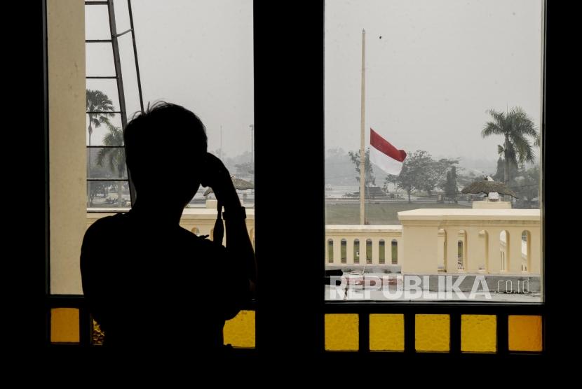 Pengunjung memotret bendera setengah tiang berkibar di Istana Siak Sri Indrapura, Kabupaten Siak, Riau, Selasa (10/9).