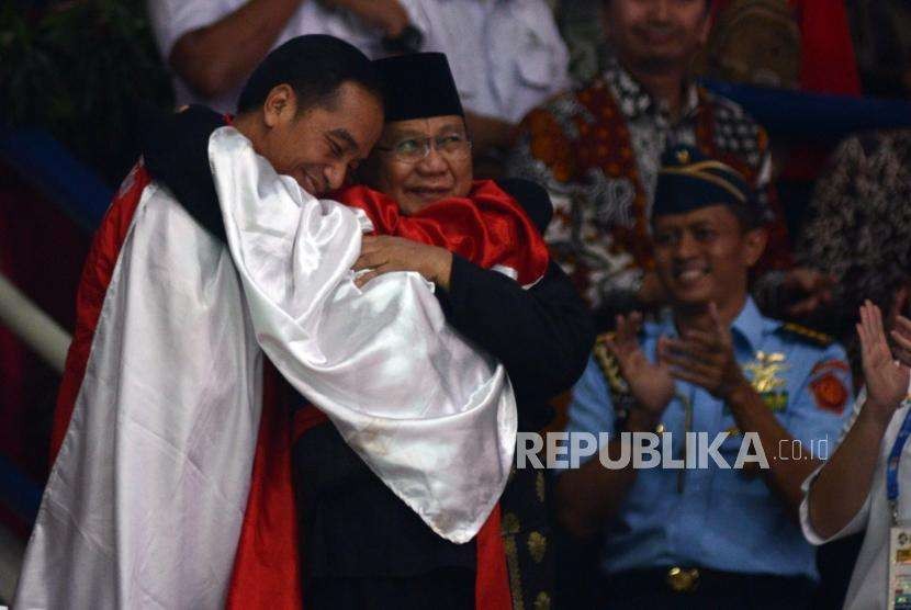 Presiden Joko Widodo bersama Ketua Umum Pengurus Besar Ikatan Pencak Silat Seluruh Indonesia Prabowo Subianto dan Pesilat Indonesia Hanifan Yudani Kusumah berpelukan usai pertandingan cabang olahraga silat Asian Games 2018 di Padepokan Pencak Silat TMII, Jakarta, Rabu (29/8).