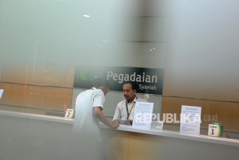 Petugas melayani nasabah ketika bertransaksi di kantor pelayanan Pegadaian Syariah, Jakarta, Jumat (4/1).
