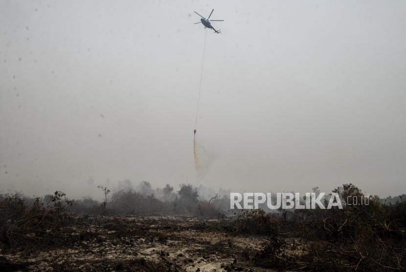 Helikopter BNPB menyiramkan air pada lahan yang terbakar di Desa Rimbo Panjang, Kabupaten Kampar, Riau, Selasa (17/9).