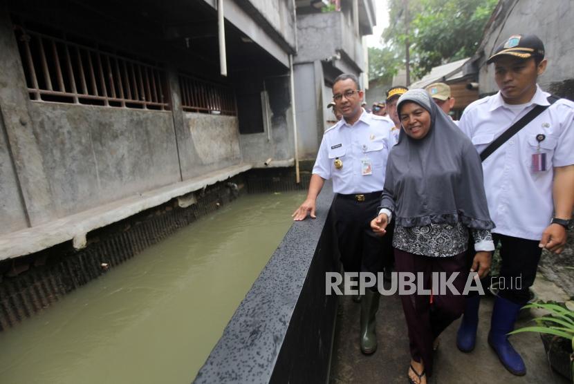 Gubernur DKI Jakarta Anies Baswedan meninjau aliran sungai bersama warga saat perbaikan tanggul Kali Pulo yang jebol akibat hujan ekstrem terjadi pada Senin (11/12) siang di Kelurahan Jatipadang, Pasar Minggu, Jakarta, Rabu (13/12).