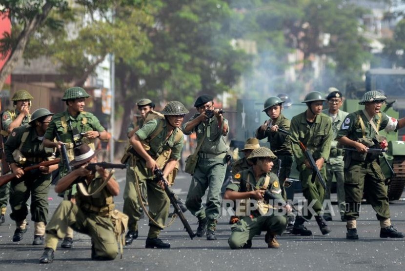 Peserta meakukan aksi teatrikal peperangan ketika mengikuti Parade Surabaya Juang saat melintas di jalan Tunjungan, Surabaya, Jawa Timur, Ahad (5/11).
