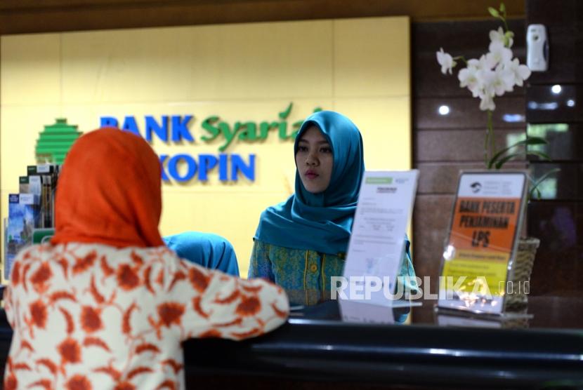 Petugas melayani transaksi nasabah di kantor layanan Bank Syariah Bukopin, Jakarta, Selasa (2/1).
