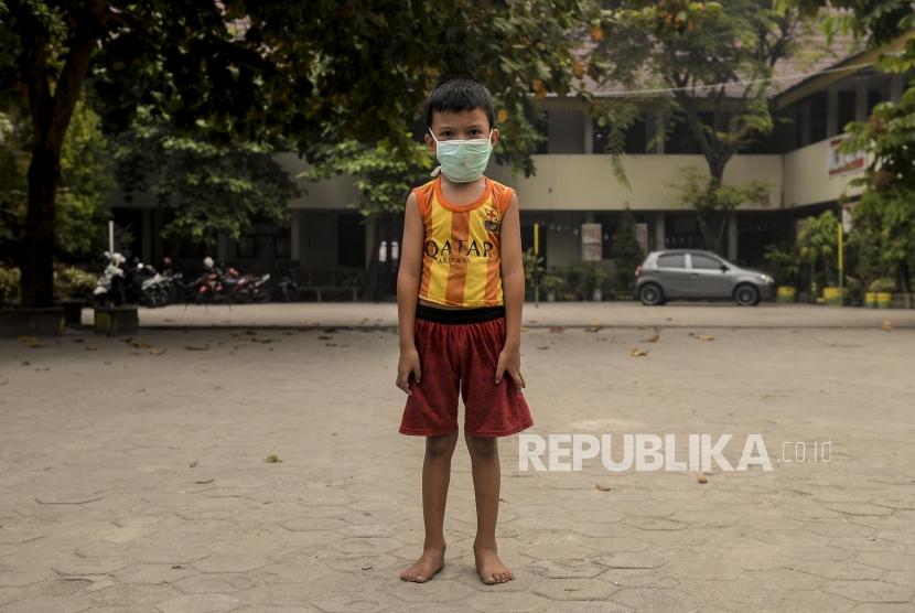 Tomi memakai masker untuk menghalau kabut asap kebakaran hutan dan lahan di Pekanbaru, Riau, Kamis (19/9).