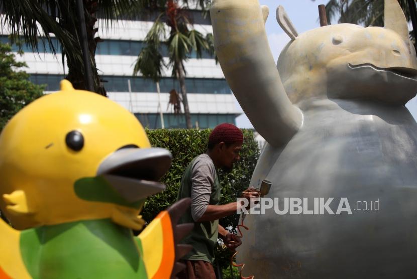 Pekerja menyelesaikan pengecatan patung maskot Asian Games yang akan dipasang di Depan Gedung Balai Kota, Jakarta, Kamis (5/7).