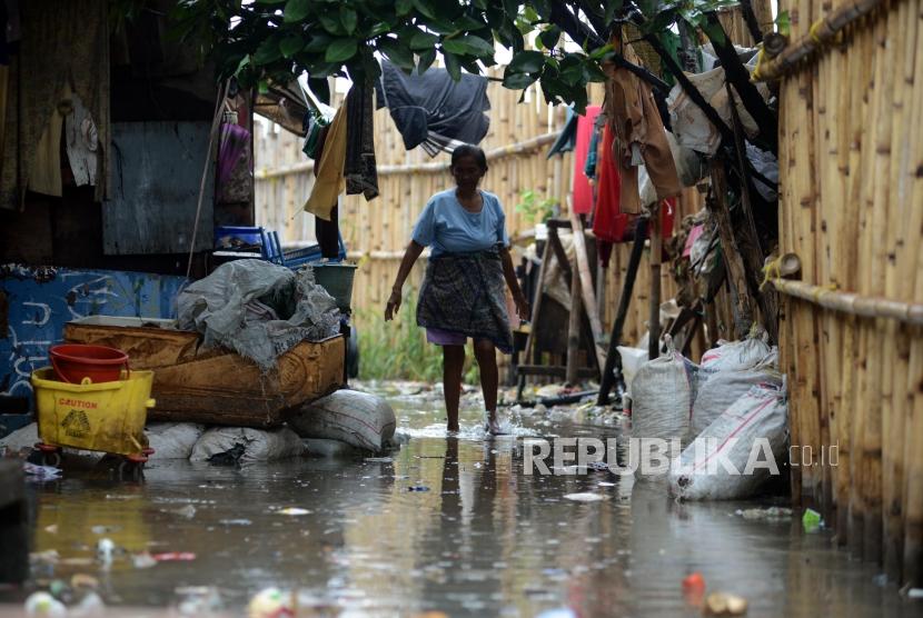 Warga melintasi genangan air saat terjadi banjir rob di kawasan Muara Angke, Kecamatan Pluit, Jakarta Utara, Selasa (22/1).