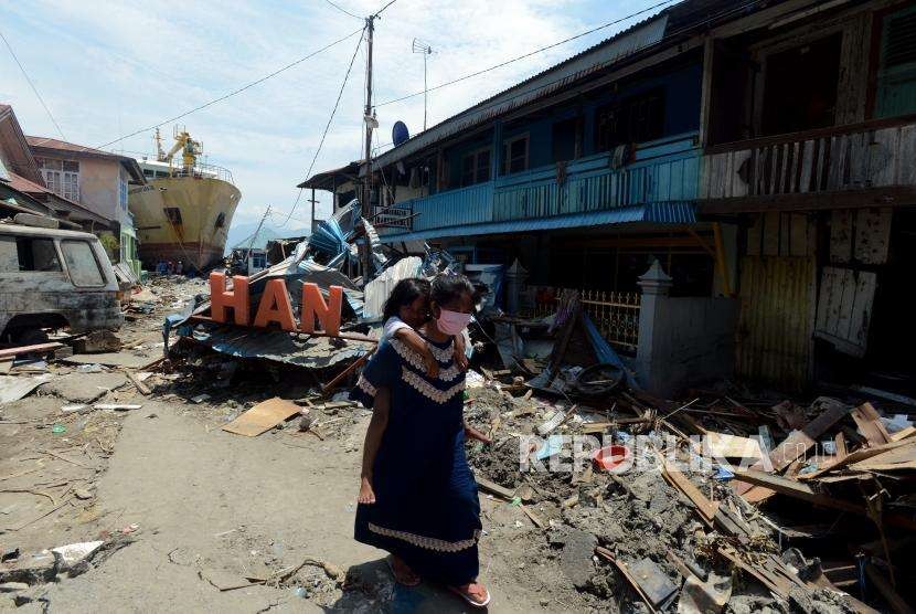 Sejumlah warga berjalan didekat bangunan yang runtuh di Pelabuhan Wani, Palu, Sulawesi Tengah, Kamis (4/10).