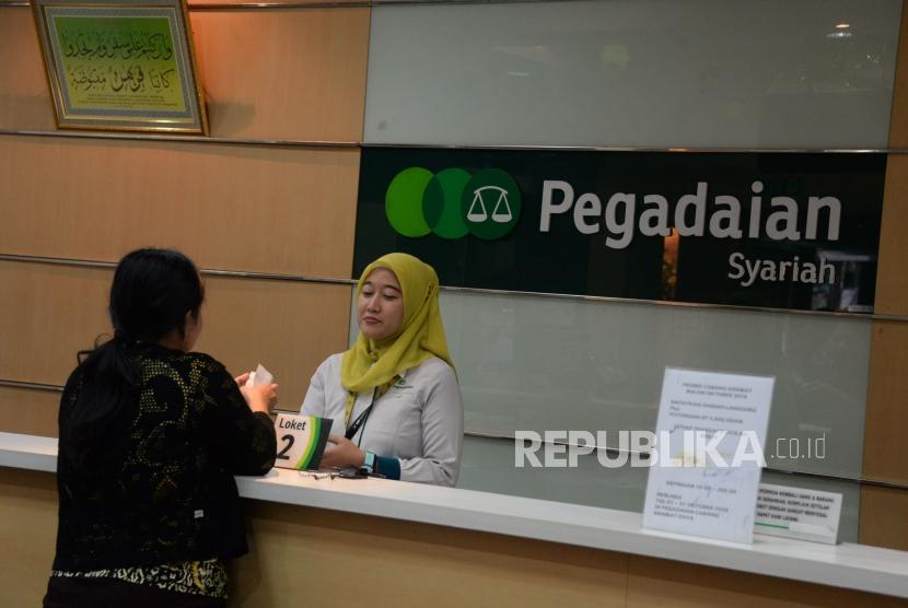 Petugas melayani nasabah ketika bertransaksi di kantor pelayanan Pegadaian Syariah, Jakarta, Senin (15/10).