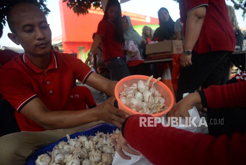 Petugas menimbang bawang putih ketika gelar pangan murah berkualitas di Toko Tani Indonesia Center, Jakarta, Ahad (5/5).