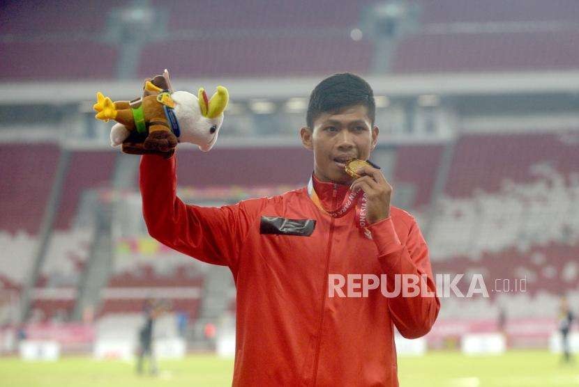 Sprinter Indonesia Sapto Yogo Purnomo menggigit medali   usa penyerahan medali emas  final 100 meter putra T37 Asian Para Games di Stadion Utama Gelora Bung Karno, Senayan, Jakarta, Selasa  (9/10).