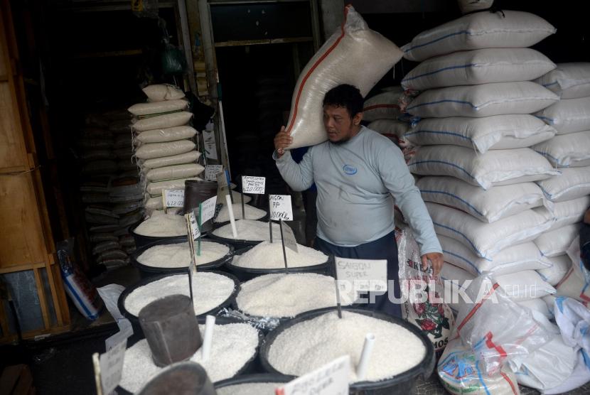 Pedagang memindahkan karung beras di salah satu agen penjual beras di Kawasan Manggarai, Jakarta, Ahad (4/3).