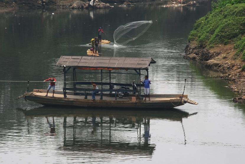 Penarik eretan membawa pelanggannya menyebrangi sungai Cisadane di Neglasari, Tangerang, Banten, Selasa (5/9).