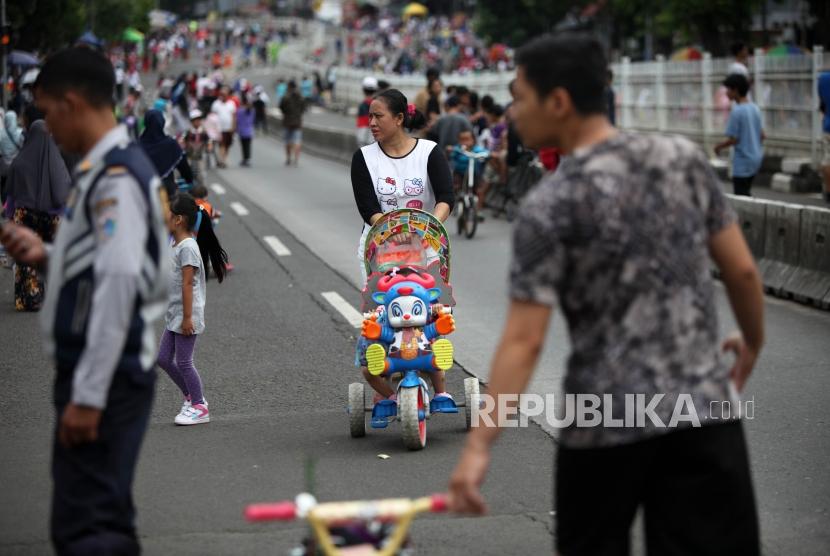 Warga membawa anaknya berjalan saat hari bebas kendaraan bermotor (HBKB) di Kawasan Mampang, Jakarta, Ahad (21/1).