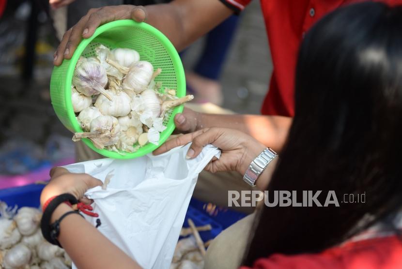 Petugas menimbang bawang putih ketika gelar pangan murah berkualitas di Toko Tani Indonesia Center, Jakarta, Ahad (5/5).